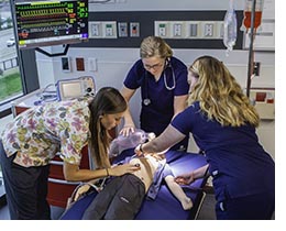 Students demonstrate assisted breathing techniques on a medical mannequin at the new PA Studies Facility
